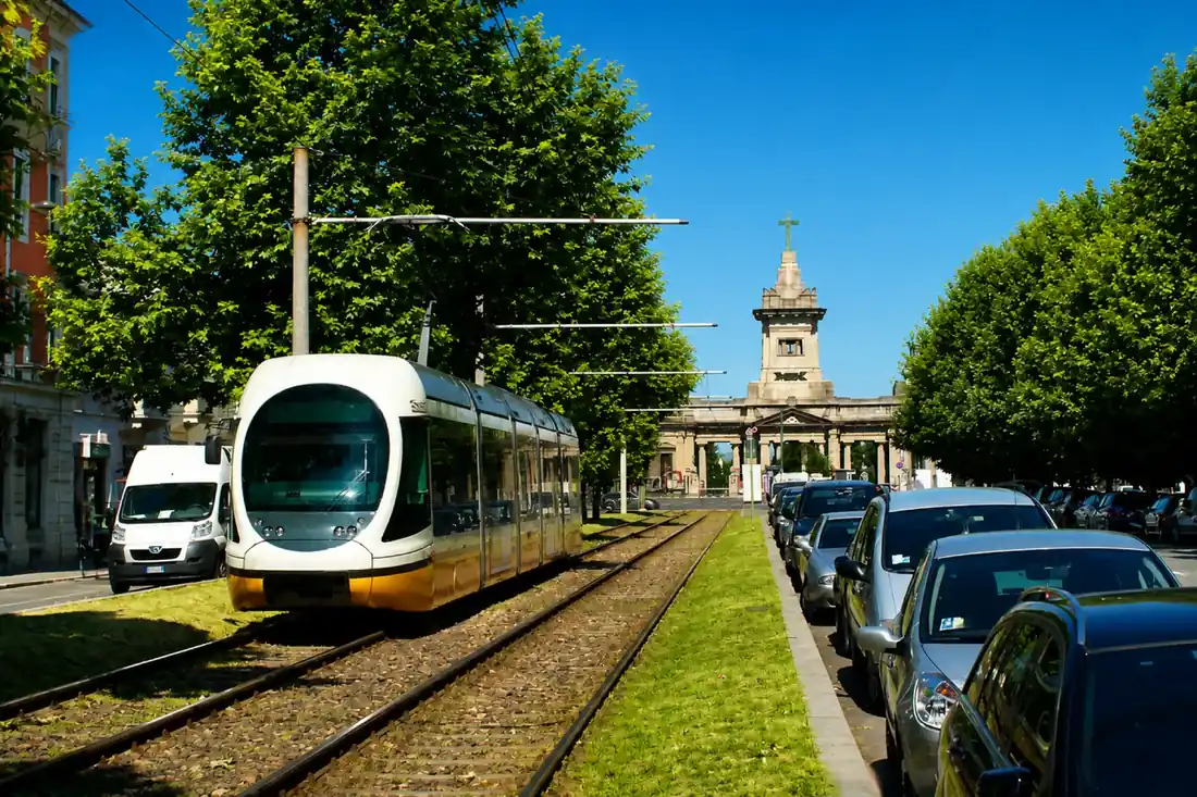 Modern Milan tram travelling along a tree-lined avenue